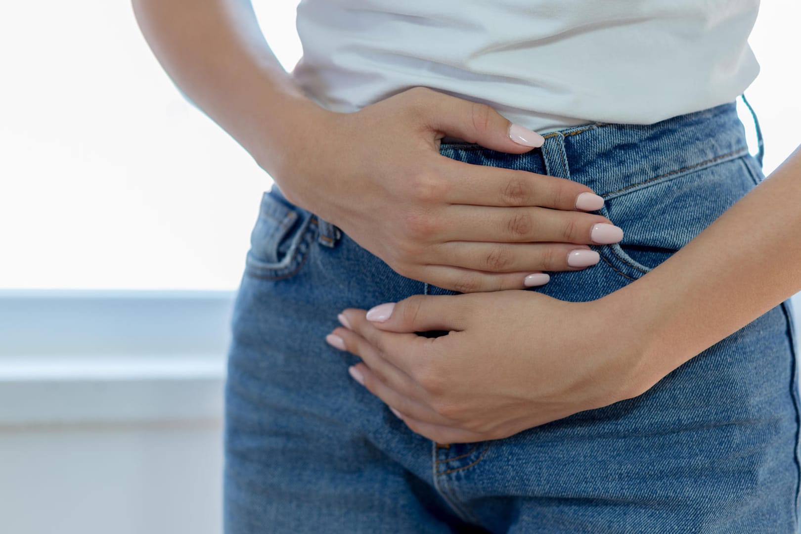 Eine Frau hält sich die Hände an den Unterbauch: Schmerzen treten in der Regel erst auf, wenn eines oder mehrere der Myome eine gewisse Größe erreicht haben.