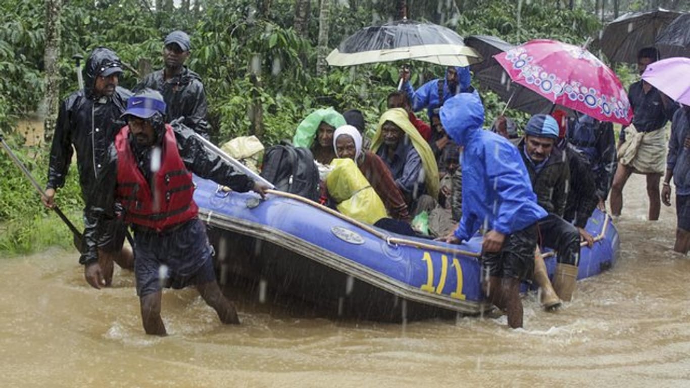 Soldaten und Freiwillige der indischen Armee ziehen Überschwemmungsopfer mit einem Schlauchboot über Wege, die unter Wasser stehen.
