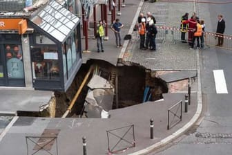 Feuerwehrleute und Bauarbeiter begutachten den Schaden in Amiens: Vor einem Restaurant hat sich ein zehn Meter breites Loch aufgetan.