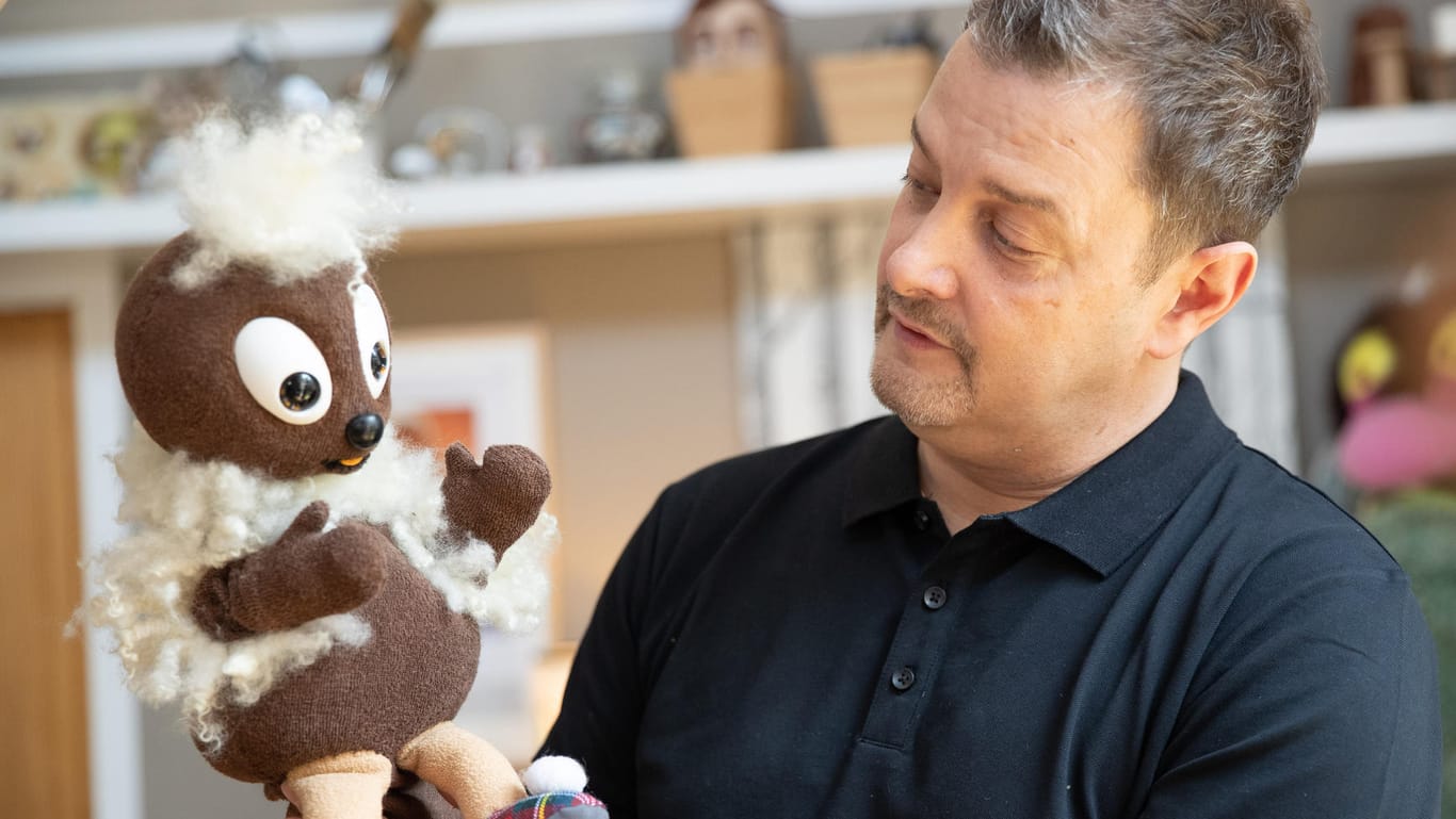 Der Figurenschneider Norman Schneider hält die Sandmännchen-Puppenfigur "Pittiplatsch" in der Hand. Norman ist freischaffender Figurenbildner und arbeitet im eigenen Atelier.