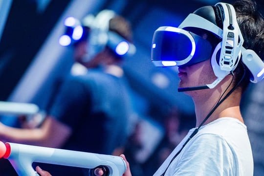Ein Besucher der Kölner Gamescom probiert an einem Stand ein Videospiel mit einer VR-Brille aus.