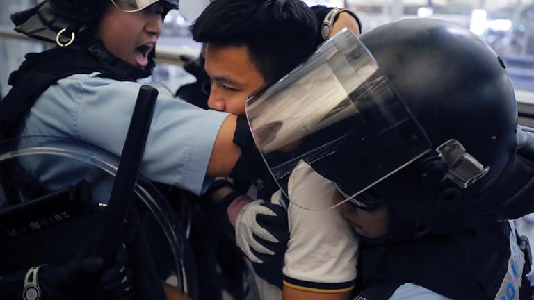 Polizisten nehmen einen Demonstranten im Hongkonger Flughafen fest.