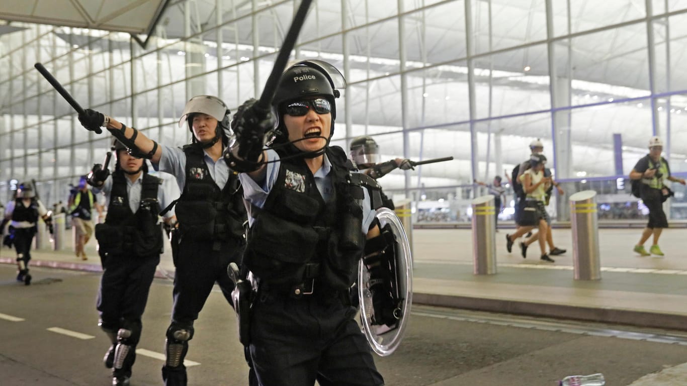 Polizisten mit Schlagstöcken schreien Demonstranten im Hongkonger Flughafen an: Bei Protesten Tausender Regierungskritiker im Flughafen Hongkong ist es am Dienstag zu gewaltsamen Zusammenstößen mit der Polizei gekommen.