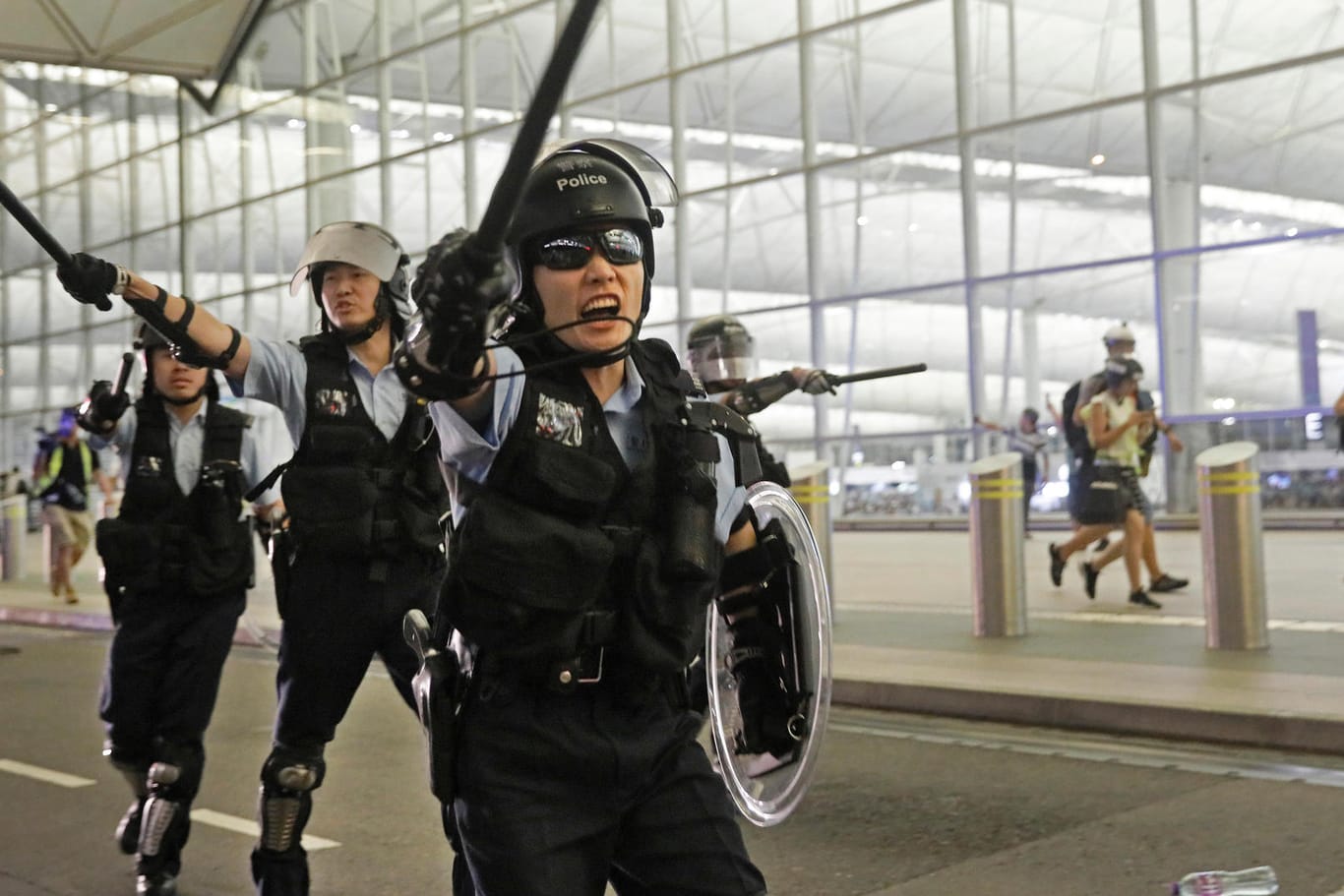 Polizisten mit Schlagstöcken schreien Demonstranten im Hongkonger Flughafen an: Bei Protesten Tausender Regierungskritiker im Flughafen Hongkong ist es am Dienstag zu gewaltsamen Zusammenstößen mit der Polizei gekommen.
