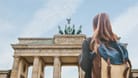 Eine junge Frau betrachtet das Brandenburger Tor. Testen Sie Ihr Wissen im Deutschland-Quiz.