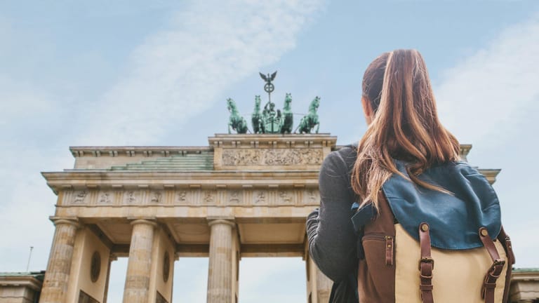 Eine junge Frau betrachtet das Brandenburger Tor. Testen Sie Ihr Wissen im Deutschland-Quiz.