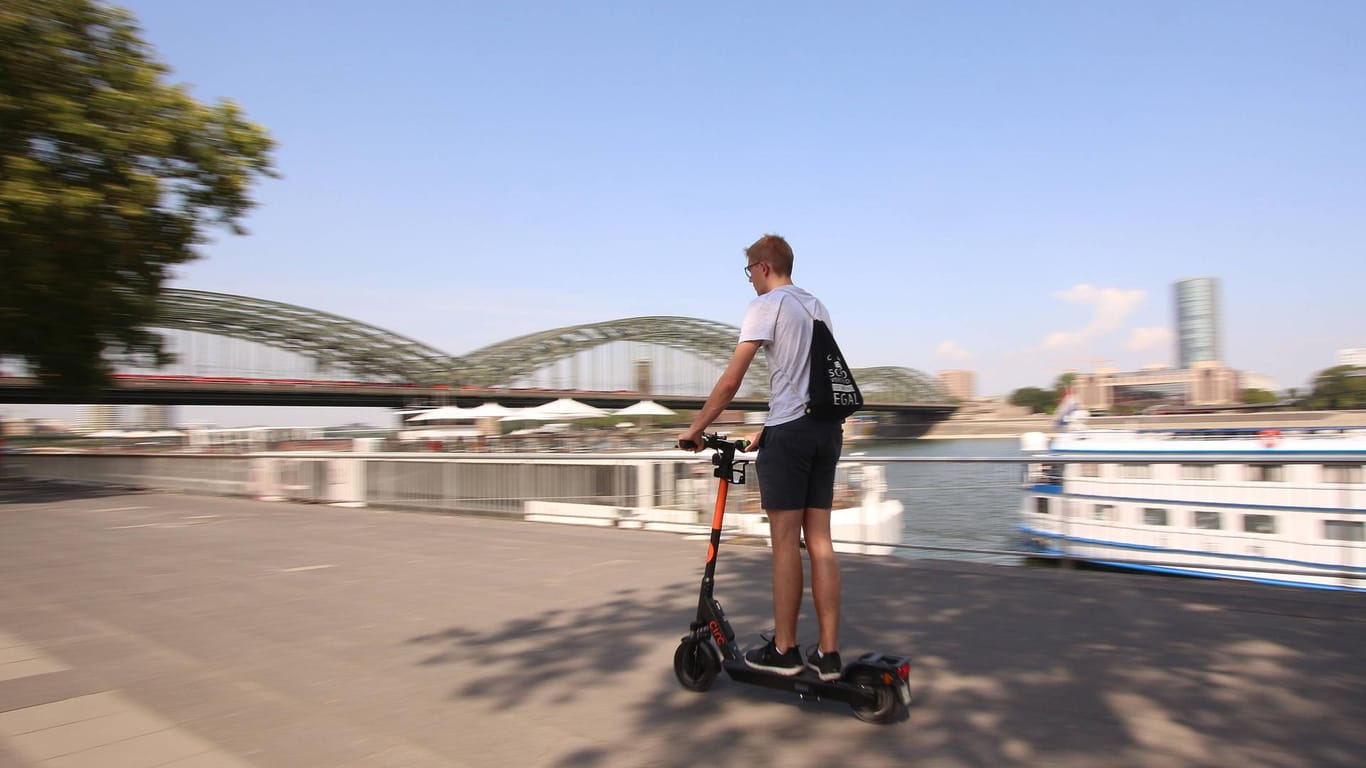 Mann fährt mit einem E-Scooter auf der Uferpromenade in Köln: In Köln-Braunsfeld sind ein E-Scooter-Fahrer und eine Radfahrerin zusammengestoßen.