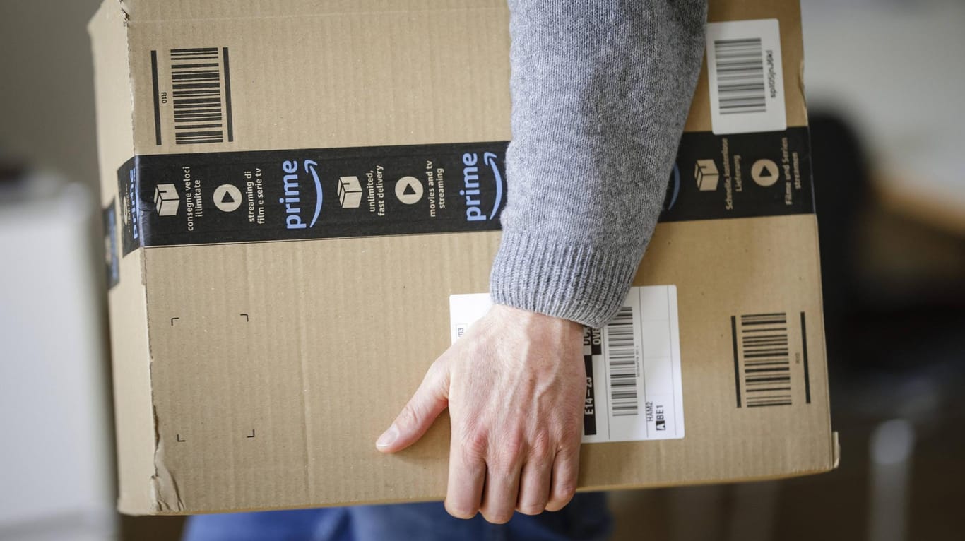 Ein Mann trägt ein Amazon-Paket: In den USA und England sollen zurückgeschickte Artikel künftig gespendet werden.