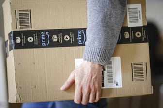 Ein Mann trägt ein Amazon-Paket: In den USA und England sollen zurückgeschickte Artikel künftig gespendet werden.