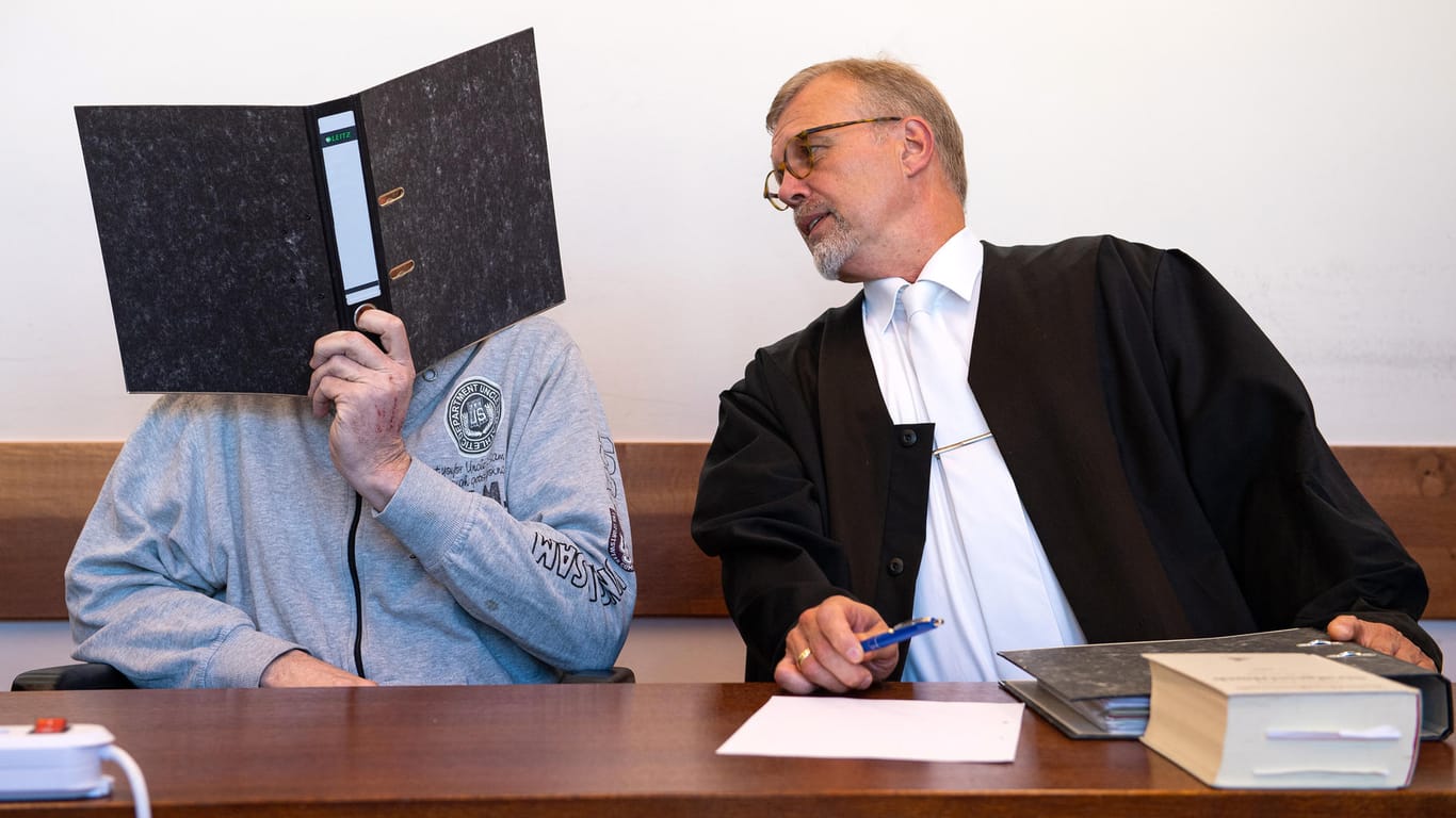 Detmold: Der Angeklagte Andreas V. (l) sitzt mit einem Aktenordner vor dem Gesicht neben seinem Anwalt Johannes Salmen.