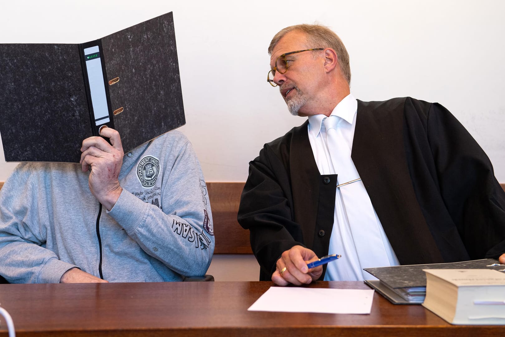 Detmold: Der Angeklagte Andreas V. (l) sitzt mit einem Aktenordner vor dem Gesicht neben seinem Anwalt Johannes Salmen.