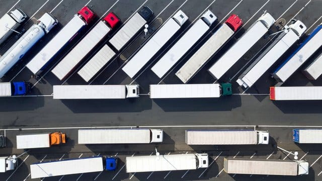 Blick aus der Luft auf abgestellte Lastwagen auf einer Rastätte.