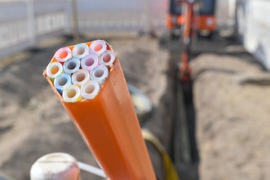 Farbige Leerrohre, in die später Glasfaserkabel verlegt werden, auf einer Baustelle in Brandenburg.