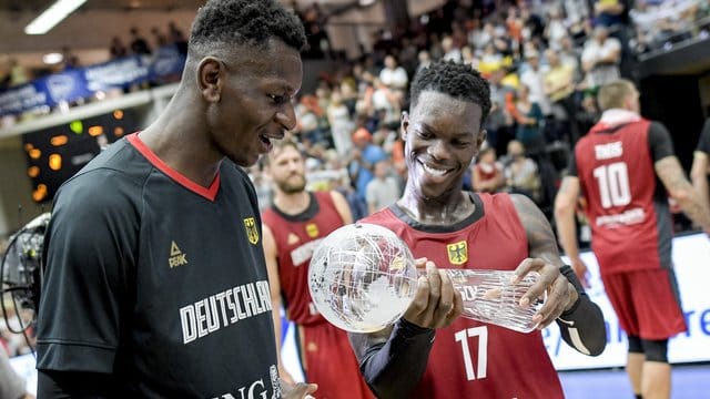 Dennis Schröder (r) und Isaac Bonga halten den Pokal in den Händen.