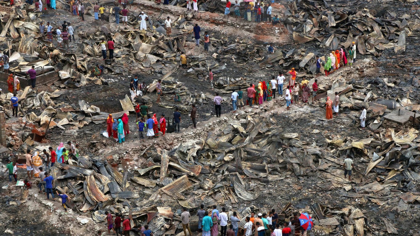 Bewohner stehen in einem vom Feuer verwüsteten Slum im Stadtteil Mirpur von Bangladeschs Hauptstadt Dhaka.