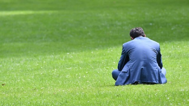 Alle Arbeitnehmer brauchen Pausen: Dieser Mann entspannt sich bei Sonnenschein auf einer Wiese.