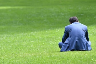 Alle Arbeitnehmer brauchen Pausen: Dieser Mann entspannt sich bei Sonnenschein auf einer Wiese.