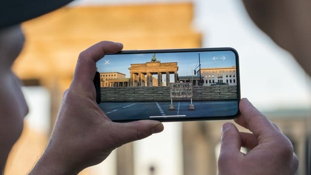 Apple-Chef Tim Cook lässt sich am Brandenburger Tor von Entwickler Peter Kolski das Projekt "MauAR" auf einem Smartphone erklären. Apple-Chef Tim Cook lässt sich am Brandenburger Tor von Entwickler Peter Kolski das Projekt "MauAR" auf einem Smartphone erklären.