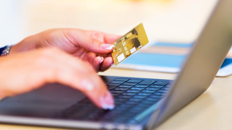 Bankkundin hält Kreditkarte in der Hand: Wer sein Konto online verwaltet, bekommt oft günstigere Konditionen.
