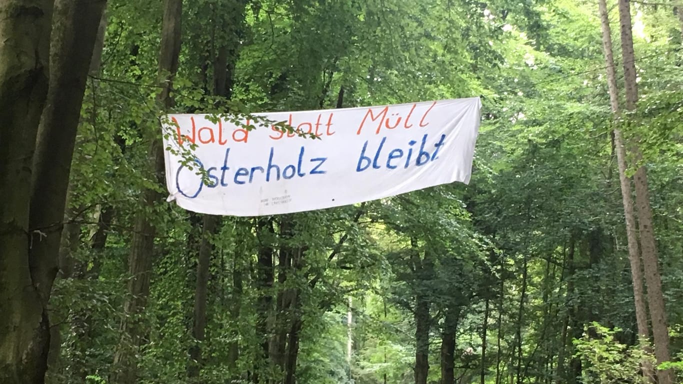 Ein Plakat mit der Aufschrift "Wald statt Müll. Osterholz bleibt" hängt zwischen Bäumen: Aktivisten wollen so auf die geplante Rodung des Waldes aufmerksam machen.