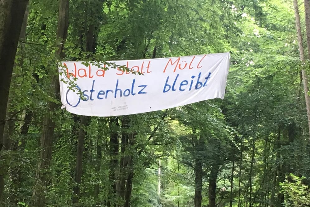 Ein Plakat mit der Aufschrift "Wald statt Müll. Osterholz bleibt" hängt zwischen Bäumen: Aktivisten wollen so auf die geplante Rodung des Waldes aufmerksam machen.