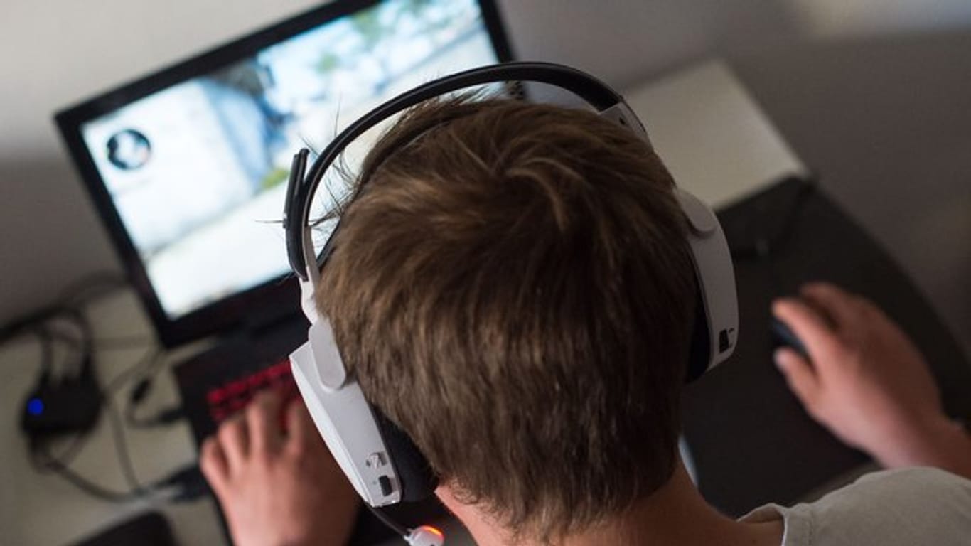 Ein junger Mann mit Headset bei einem Online-Computerspiel.