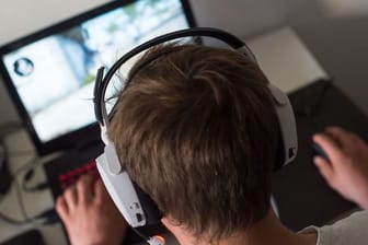 Ein junger Mann mit Headset bei einem Online-Computerspiel.