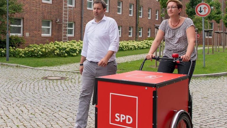 Lars Klingbeil, SPD-Generalsekretär, und Klara Geywitz, SPD-Landtagsabgeordnete in Brandenburg, gehen mit einem Lastenfahrrad mit dem Logo der SPD über das Gelände der Filmstudios Babelsberg.