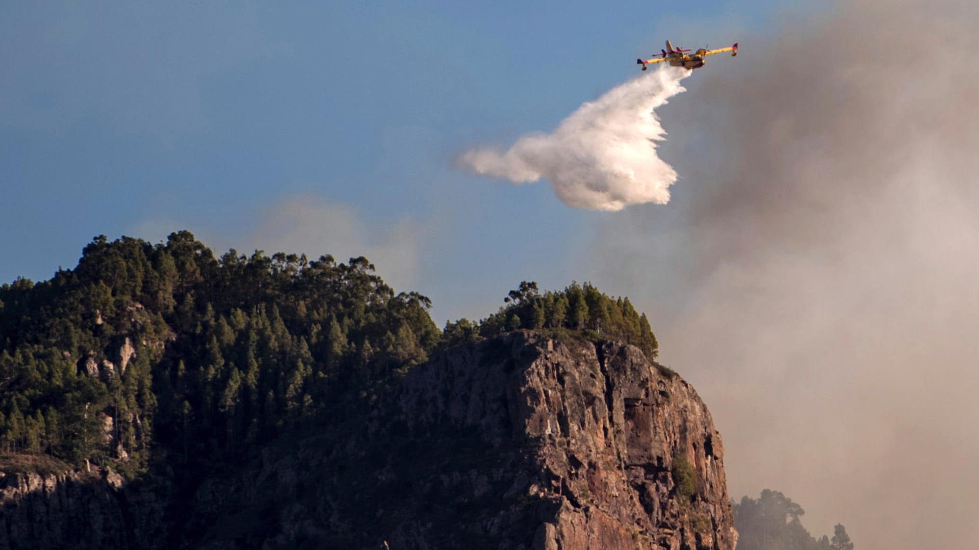 Ein Löschflugzeug fliegt über einem Waldbrand: Zahlreiche Löschflugzeuge und Hubschrauber sind in die Luft gestiegen, um gegen die Flammen in den Bergen zu kämpfen.