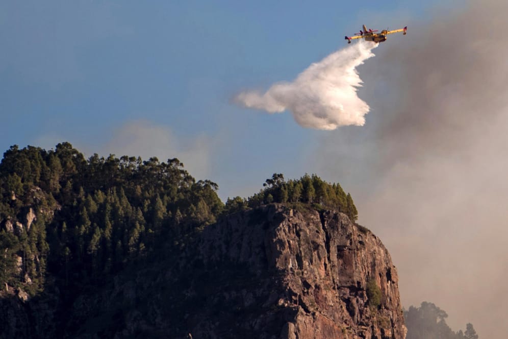 Ein Löschflugzeug fliegt über einem Waldbrand: Zahlreiche Löschflugzeuge und Hubschrauber sind in die Luft gestiegen, um gegen die Flammen in den Bergen zu kämpfen.
