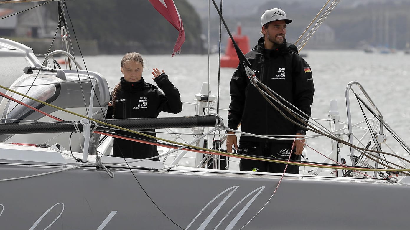 Greta Thunberg (li.), Klimaaktivistin aus Schweden, und Skipper Boris Herrmann winken von Bord der Hochseejacht "Malizia": Die Segeljacht befindet sich im Zeitplan auf ihrer Fahrt nach New York.