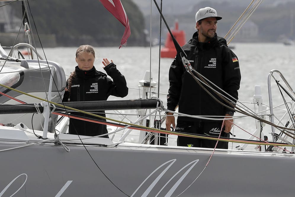 Greta Thunberg (li.), Klimaaktivistin aus Schweden, und Skipper Boris Herrmann winken von Bord der Hochseejacht "Malizia": Die Segeljacht befindet sich im Zeitplan auf ihrer Fahrt nach New York.