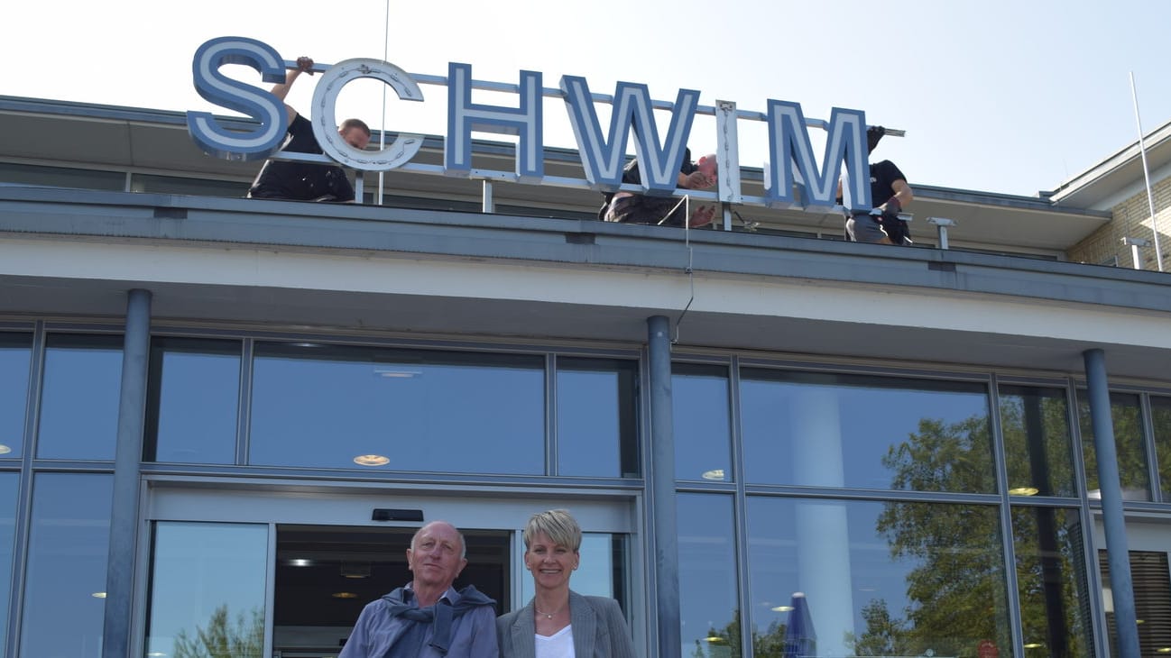 Auf einem Gebäude werden Buchstaben angebracht: Das Stadtbad am Johannesberg in Wuppertal trägt jetzt den Schriftzug "Schwimmoper".