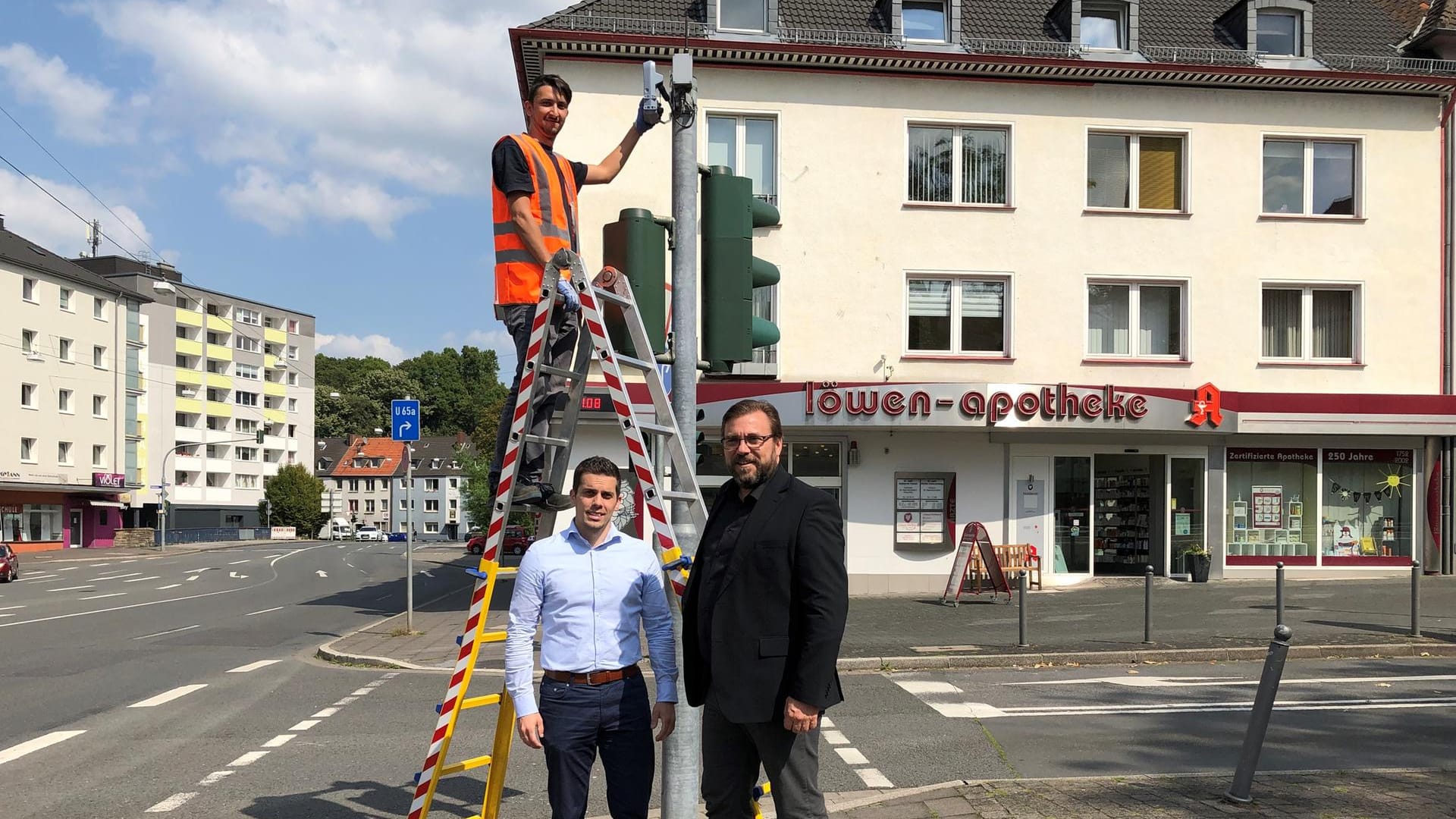 Drei Männer stehen an einer Ampel in Hagen: Markus Falkenroth (links) und der technische Beigeordnete Henning Keune am Hagener Innenstadtring, wo Techniker Emre Degirmensi eine der neuen Messstellen installiert.