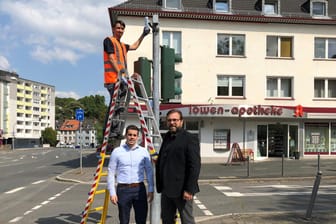 Drei Männer stehen an einer Ampel in Hagen: Markus Falkenroth (links) und der technische Beigeordnete Henning Keune am Hagener Innenstadtring, wo Techniker Emre Degirmensi eine der neuen Messstellen installiert.