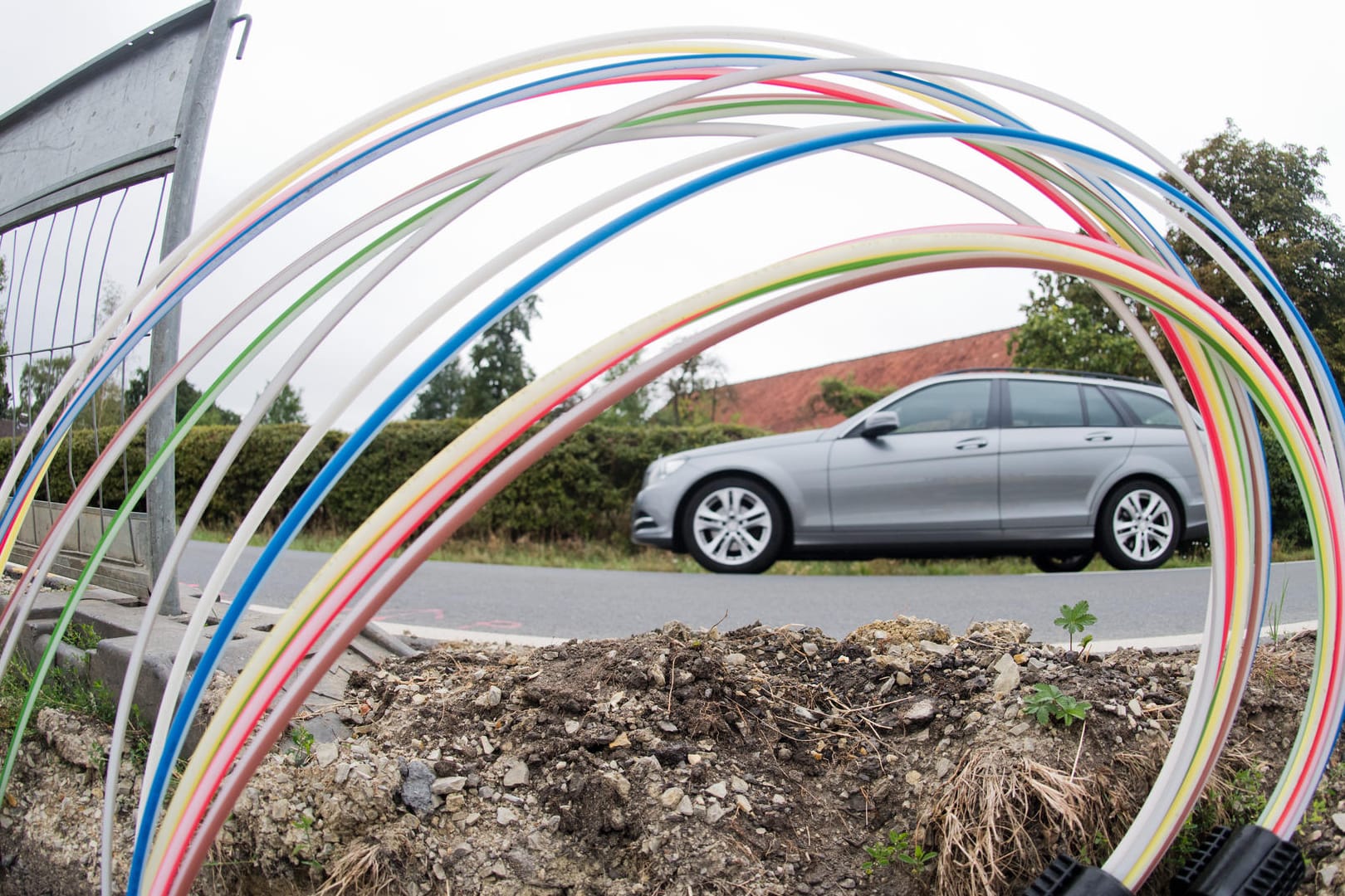 Ein Auto fährt an einer Baugrube vorbei, in der Leerrohre für Glasfaserleitungen für schnelles Internet liegen: Die Deutsche Telekom investiert in den Breitbandausbau.