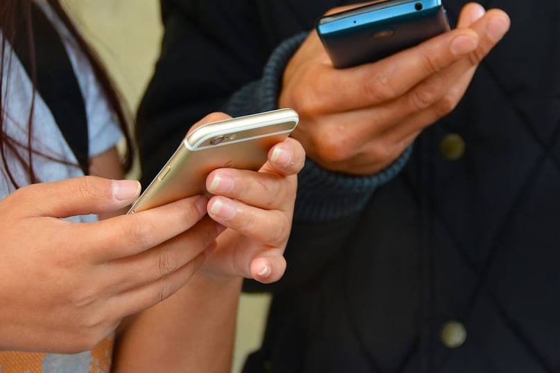 Eine Frau und ein Mann nutzen ihr Smartphone: Bei Prepaid-Tarifen variiert der Abrechnungszeitraum. Darauf sollten Verbraucher beim Preisvergleich Rücksicht nehmen.