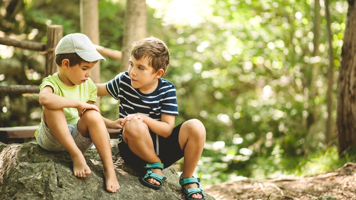 Ein Junge tröstet einen anderen: Sozialkompetenz können Kinder unter anderem lernen, indem sie sich gegenseitig unterstützen.