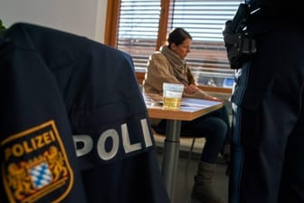 Gestellte Szene: Junge Frau sitzt auf der Wache, eine Urinprobe steht auf dem Tisch.