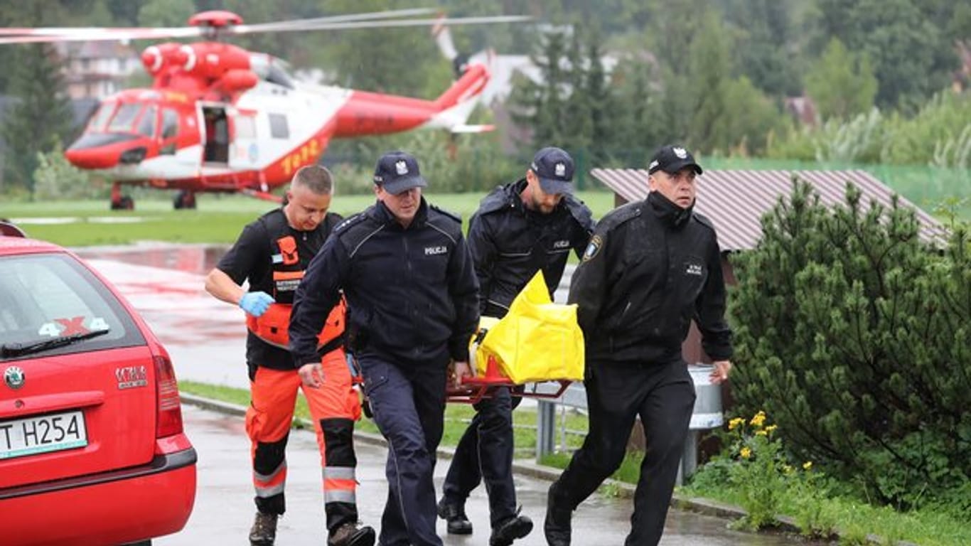 Polizisten tragen in Zakopane einen verletzten Touristen zu einem Krankenwagen.