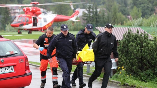 Polizisten tragen in Zakopane einen verletzten Touristen zu einem Krankenwagen. Polizisten tragen in Zakopane einen verletzten Touristen zu einem Krankenwagen.