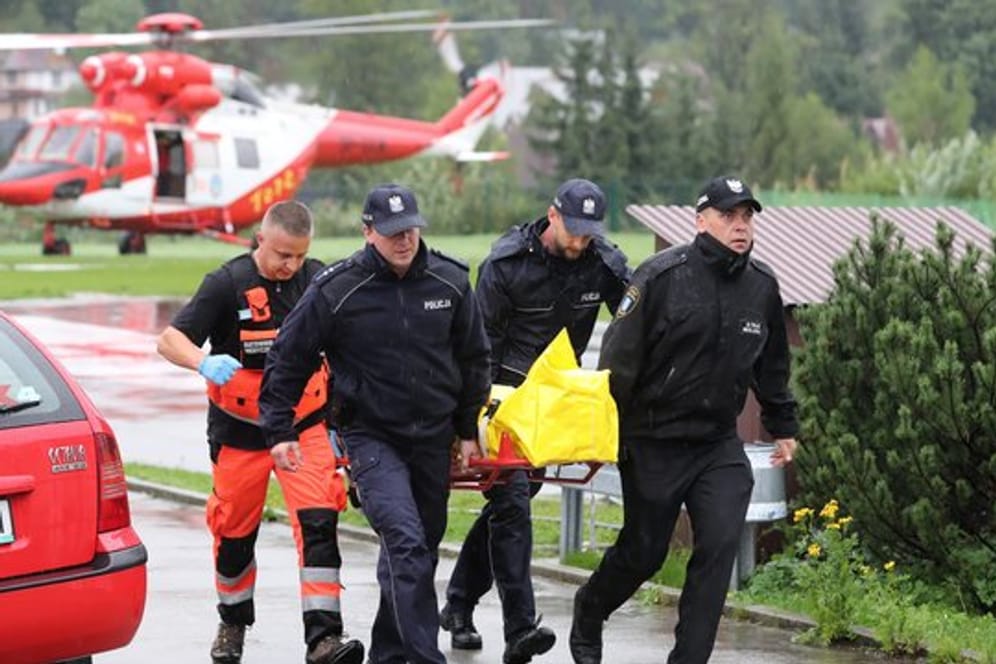 Polizisten tragen in Zakopane einen verletzten Touristen zu einem Krankenwagen.
