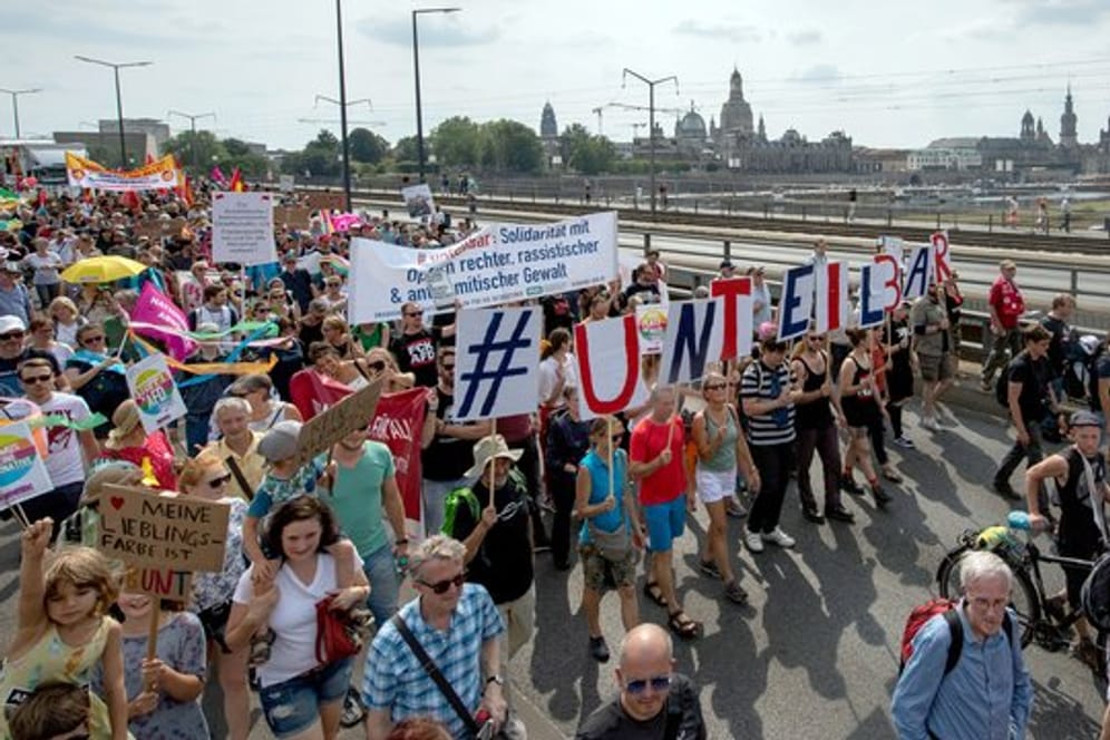 Vor der historischen Altstadtkulisse gehen Tausende Teilnehmer der Demonstration des Bündnisses #Unteilbar über die Carolabrücke in Dresden.