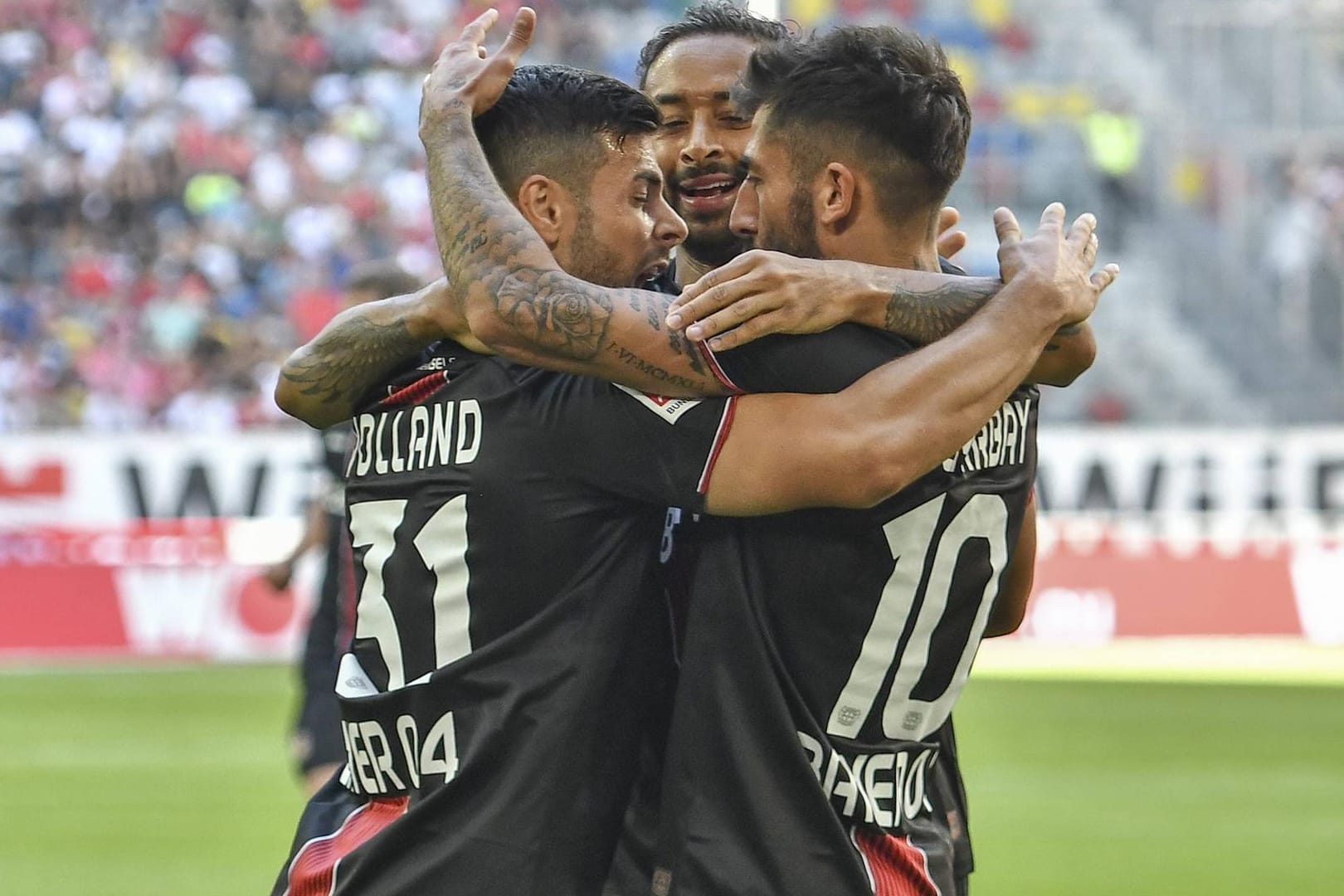 Leverkusener Jubeltrio: Kevin Volland (v. l.), Karim Bellarabi und Kerem Demirbay nach dem Führungstreffer für Bayer.