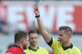 Schiedsrichter Tobias Welz (r) zeigt Paderborn-Trainer Baumgart (l) die erste Gelbe Karte.