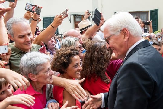 Bundespräsident Frank-Walter Steinmeier geht nach einer Kranzniederlegung für die Opfer des Massakers von Fivizzano durch den Ort und begrüßt Besucher.