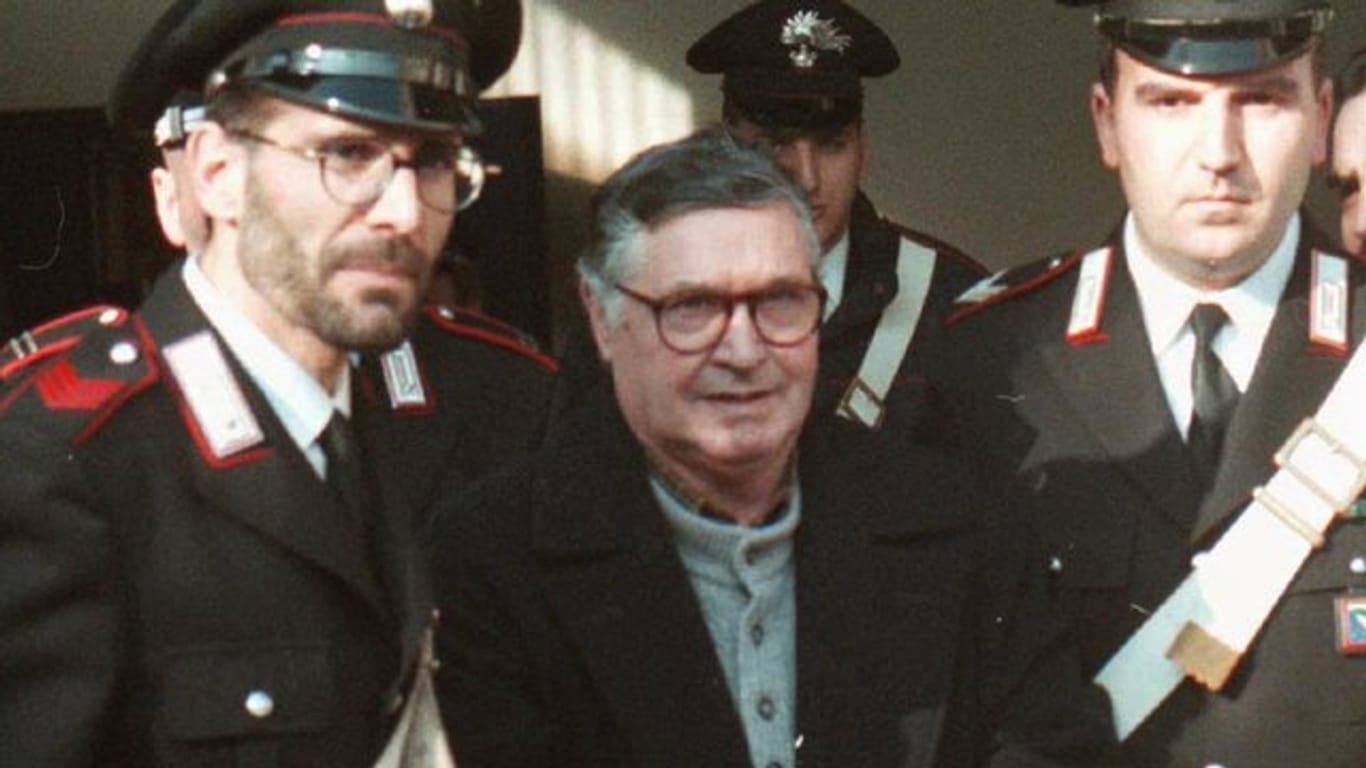 Der italienische Mafiaboss Salvatore Riina (M) wird von Polizisten in Handschellen in den Gerichtssaal geführt.
