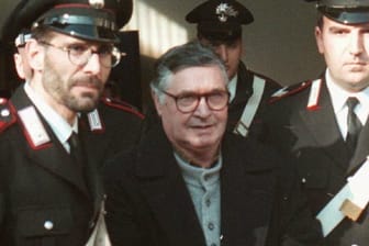Der italienische Mafiaboss Salvatore Riina (M) wird von Polizisten in Handschellen in den Gerichtssaal geführt.