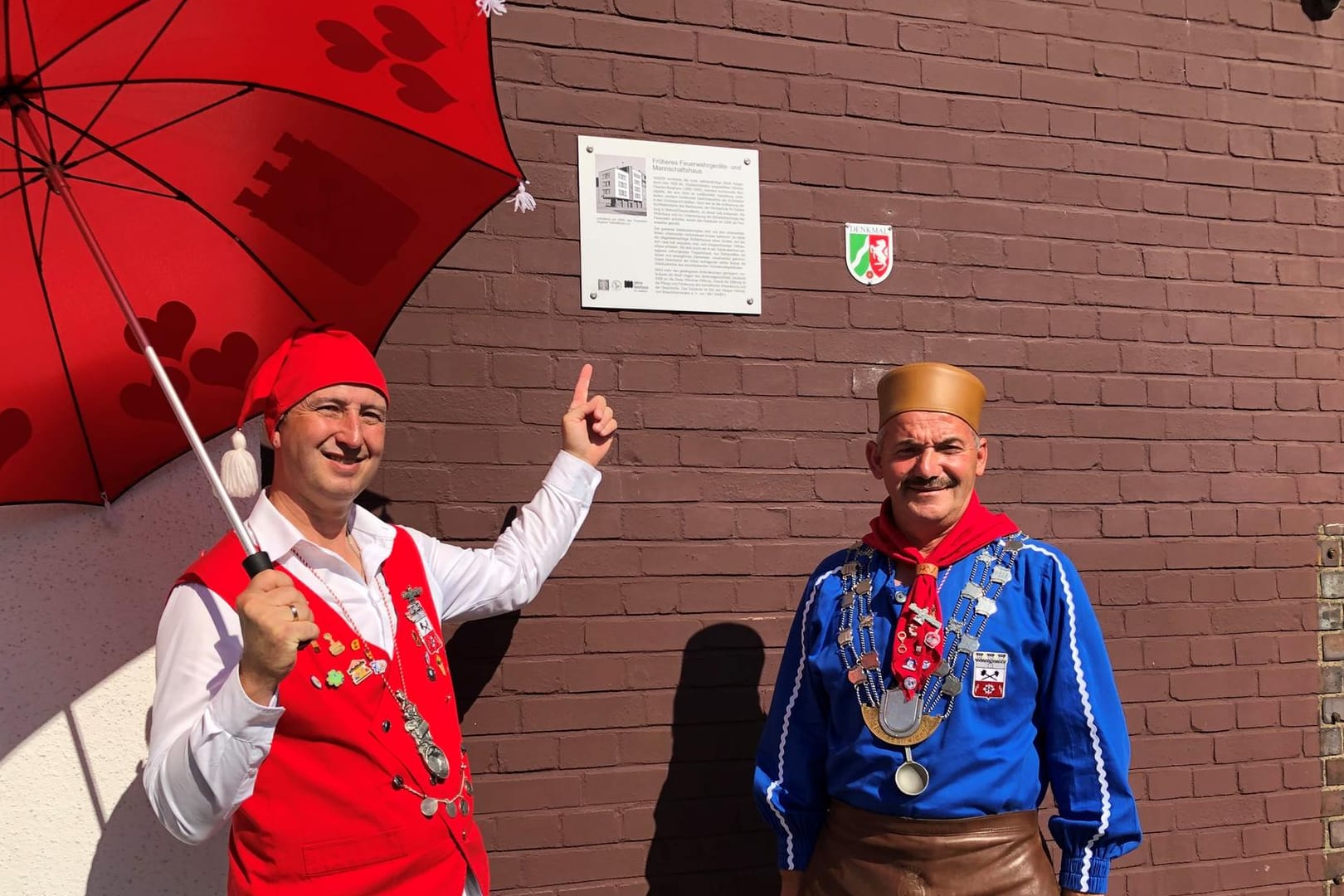 Zwei Männer stehen vor einem Schild: Zwei Symbolfiguren des Hasper Brauchtums, Kirmesbauer Michael Kröner und "Iämpestörter" Thomas Wolter, freuen sich über die neue Tafel an der alten Feuerwache.