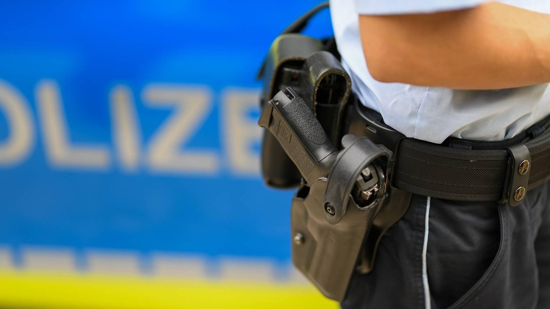 Ein Polizist steht vor einem Streifenwagen Ein Polizist steht vor einem Streifenwagen